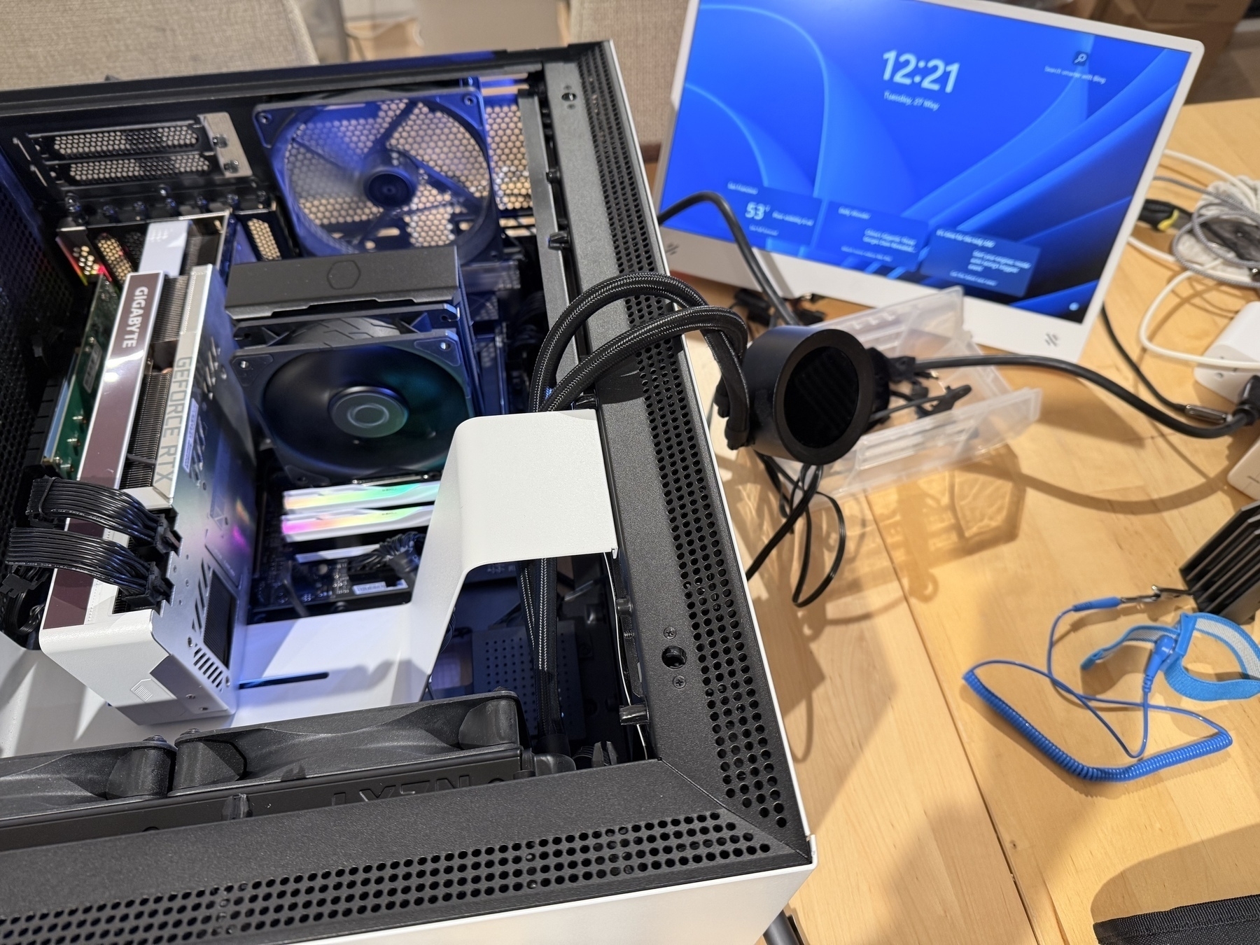 Running computer in open case next to small monitor showing Windows login screen